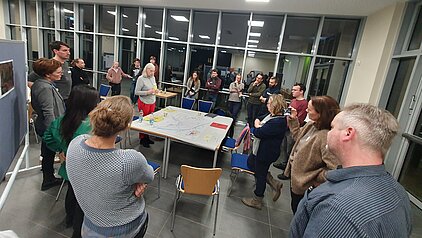 viele Menschen in einem großen Raum, die sich unterhalten und diskutieren.