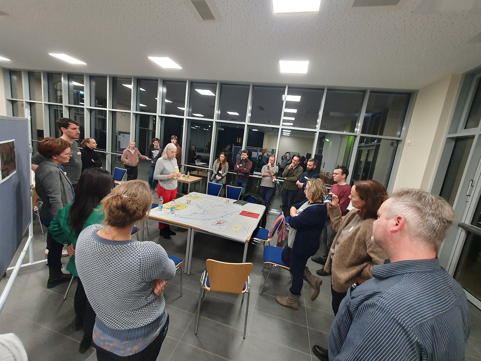 viele Menschen in einem großen Raum, die sich unterhalten und diskutieren.
