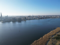 Stadtpanorama an der Unterwarnow im Vordergrund und Gebäuden am Ufer unter klarem Himmel