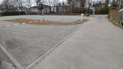 Leerer Parkplatz mit Absperrband und umliegenden Bäumen und Gebäuden im Hintergrund