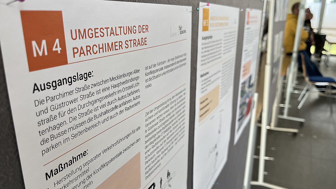 Informationsplakate zur Umgestaltung der Parchimer Straße mit Details zu Ausgangslage und Maßnahmen, aufgestellt in einem Raum mit Stühlen