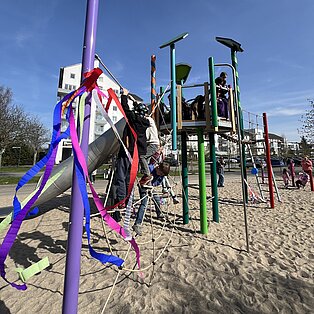 Bunte Klettergerüste und Spielgeräte auf einem Sandspielplatz unter blauem Himmel