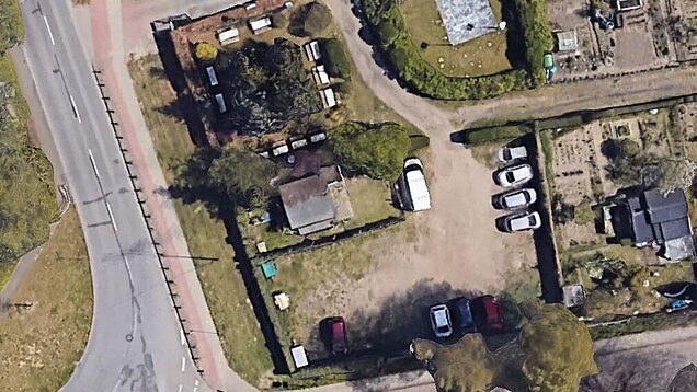 Luftaufnahme eines Kleingartengeländes mit mehreren Parzellen, Wegen und geparkten Autos an einer angrenzenden Straße - vorher