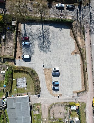 Luftaufnahme des fertiggestellten Parkplatzes der Kleingartenanlage Fährhufe in Gehlsdorf mit mehreren geparkten Autos in verschiedenen Farben und Anordnungen.