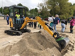 Ein gelber Bagger bei Sandarbeiten.