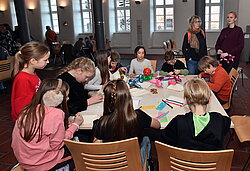 Gruppe von Menschen sitzt an einem Tisch und arbeitet gemeinsam an einem Projekt