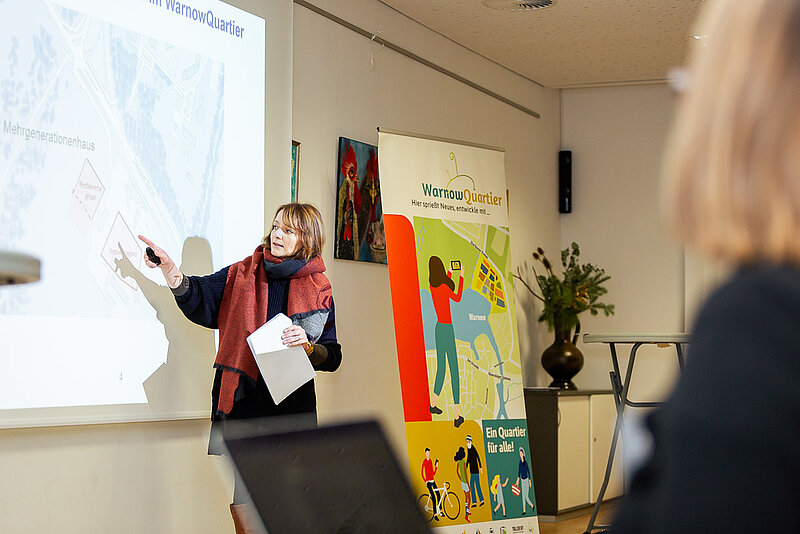 Frau präsentiert etwas auf einer Leinwand vor Publikum in einem Besprechungsraum