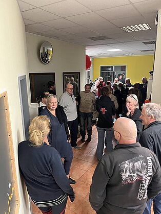 Viele Menschen stehen in einem Raum und unterhalten sich.