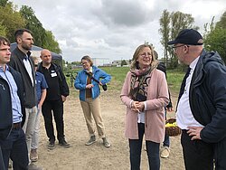 Gruppe von Menschen, die im Freien stehen und sich unterhalten.