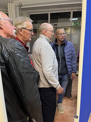 Vier Männer die auf eine Wand schauen.