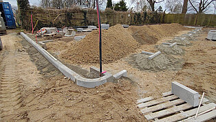 Baustelle mit aufgeschütteten Sandhaufen und verlegten Betonfundamenten für eine neue Konstruktion