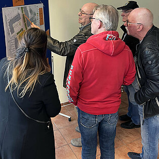 Gruppe von vier Personen, die auf eine Stellwand schauen und diskutieren.