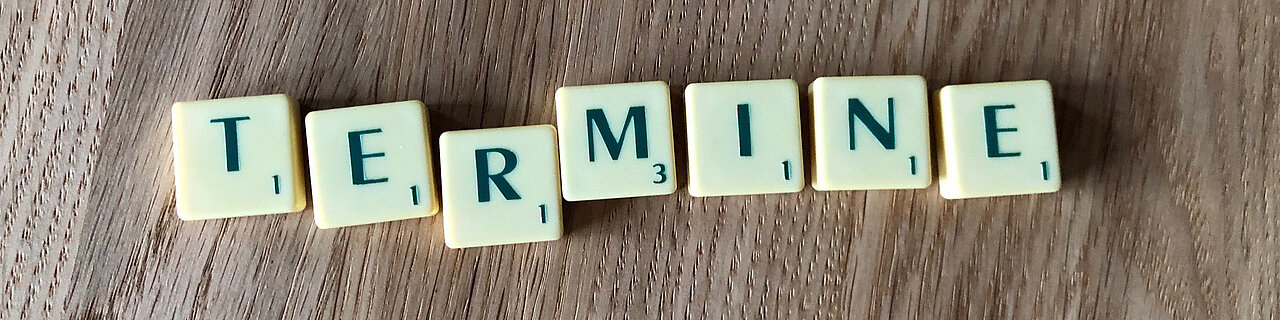 Buchstabensalat mit dem Wort 'TERMINE' aus grünen Buchstaben auf einem grauen Untergrund.