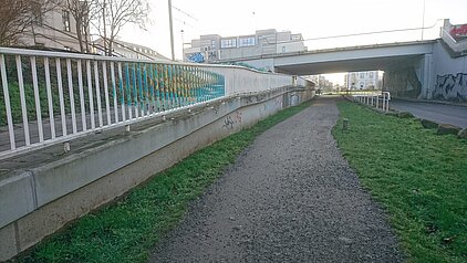 Parkplatz mit mehreren geparkten Autos und einem Parkscheinautomaten neben einem Gehweg vor einem mehrstöckigen Gebäude