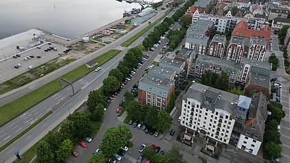 Luftaufnahme einer Stadt mit Gewässer, Straßen, Gebäuden und Grünflächen